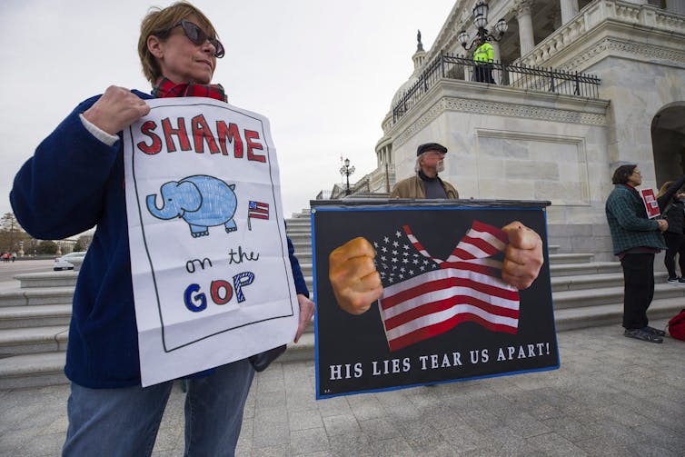Demonstrators protest outside of the U.S. Capitol with one carrying a sign that reads Shame on the GOP.