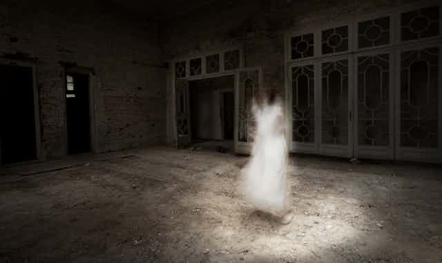 Ghostly image of young woman in white dress appears to float in the middle of an empty room.