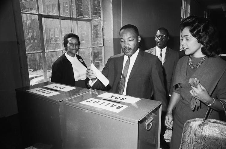 Martin Luther King Jr. votes as his wife, Coretta Scott King, waits her turn.