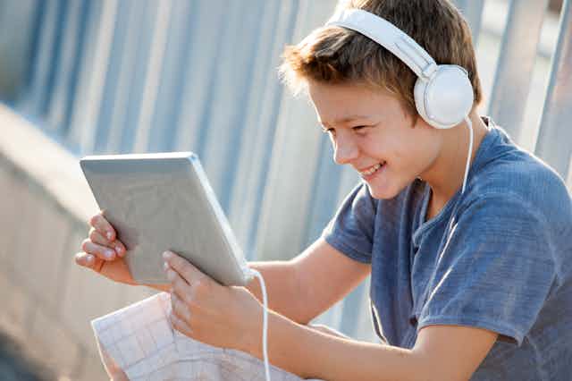 Un niño sonriente con una tableta y auriculares.