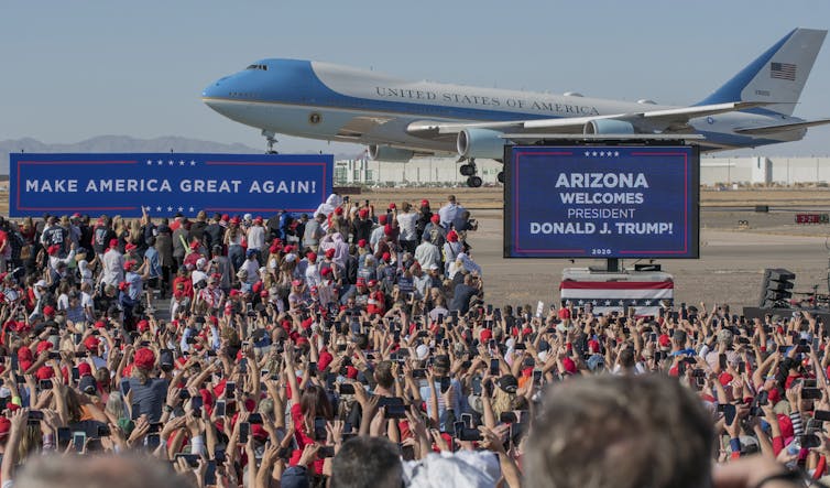Air Force One aeroplane landing with Trump supporters in front.