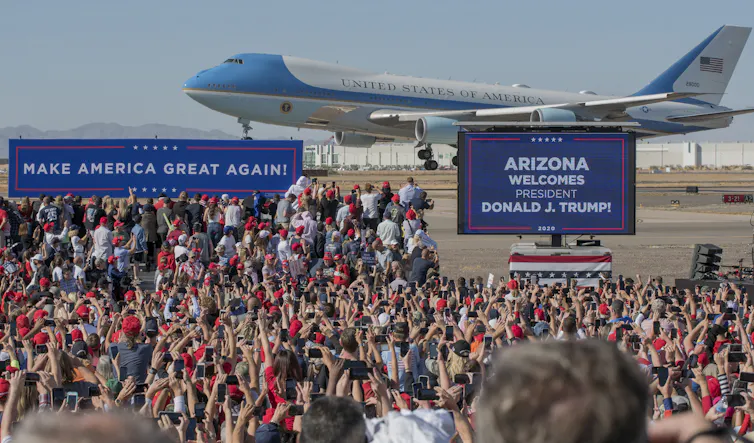 Air Force One aeroplane landing with Trump supporters in front.