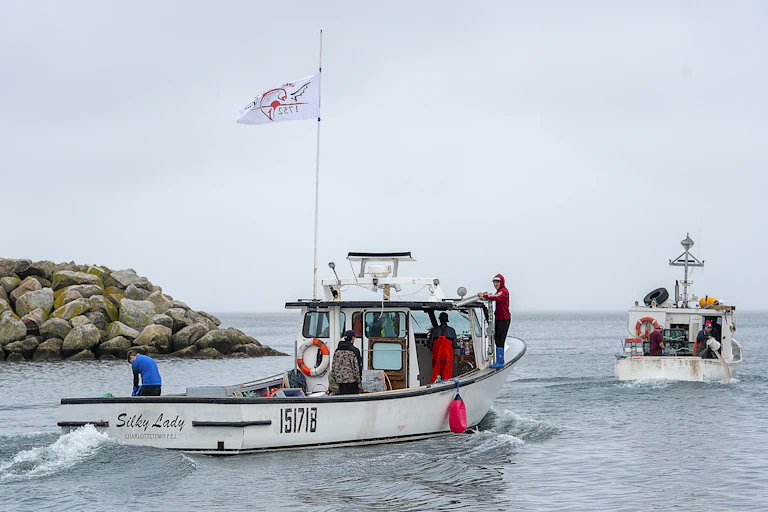 Two fishing boats motoring out of a habour