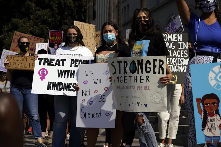 Demonstrators hold signs during a Women’s March.