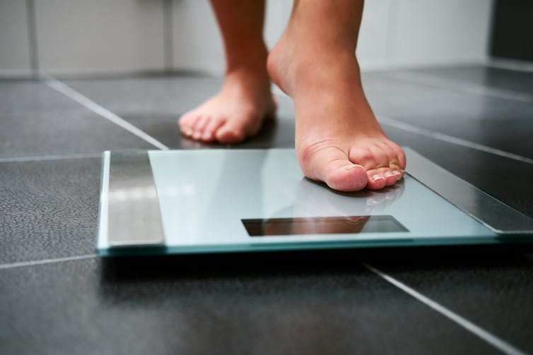 A person steps onto bathroom scales.