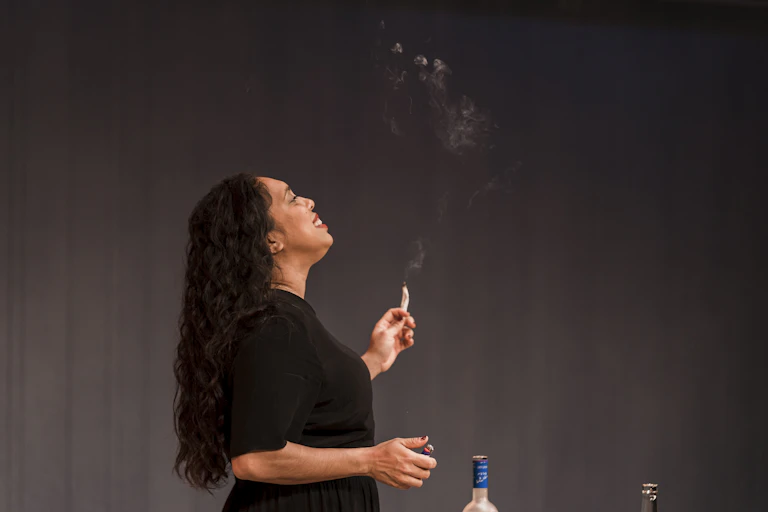 A woman smokes on stage