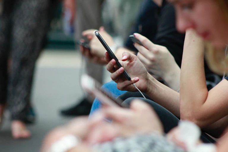 Hands of several people holding their phones.