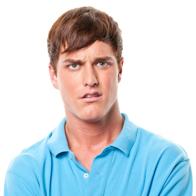 A white male college student in a light blue shirt looks upset
