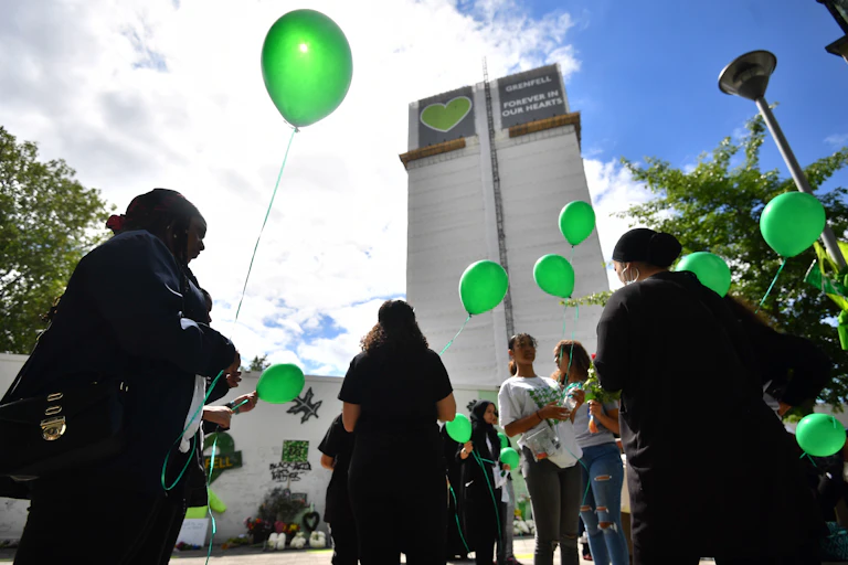 People with green balloons outside Grenfell Tower.