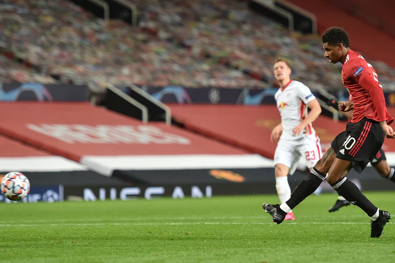 Footballer after kicking ball, other players in background
