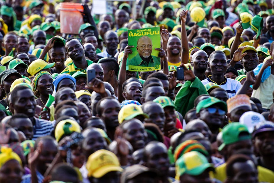 A man holds up a poster of presidential candidate John Magufuli during a ruling Chama Cha Mapinduzi (CCM) rally in Dar es Salaam, Tanzania, on October 21, 2015. CCM's party's candidate John Magufuli hopes to succeed President Jakaya Kikwete in what is seen as the tightest electoral race in Tanzania's history, as the main opposition parties unite around ex-prime minister Edward Lowassa, 61, who recently defected from the CCM