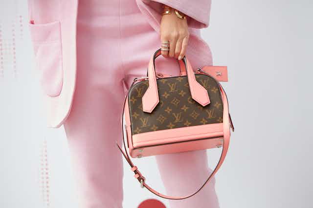 Woman in pink suit modelling a Louis Vuitton bag