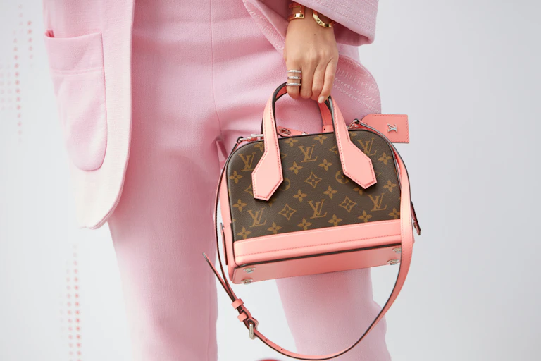 Woman in pink suit modelling a Louis Vuitton bag