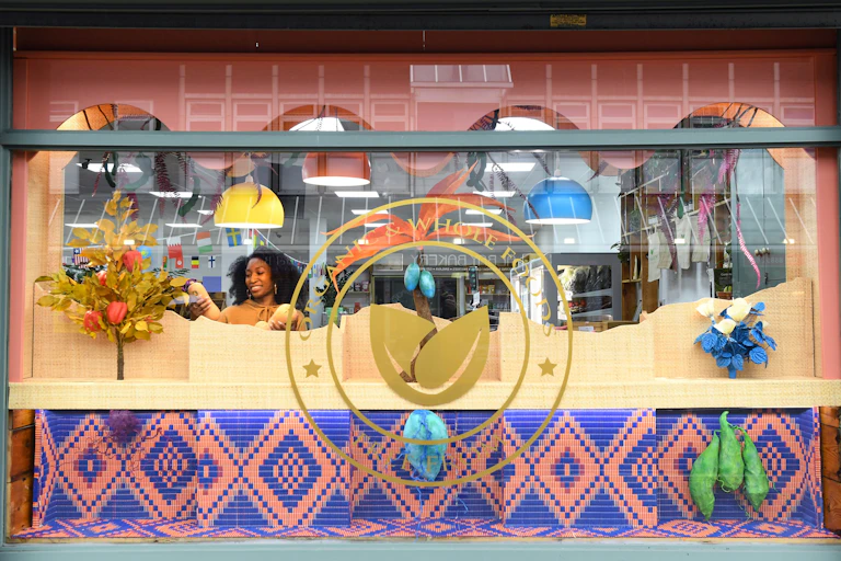 A woman arranges a colourful display in a shop window.