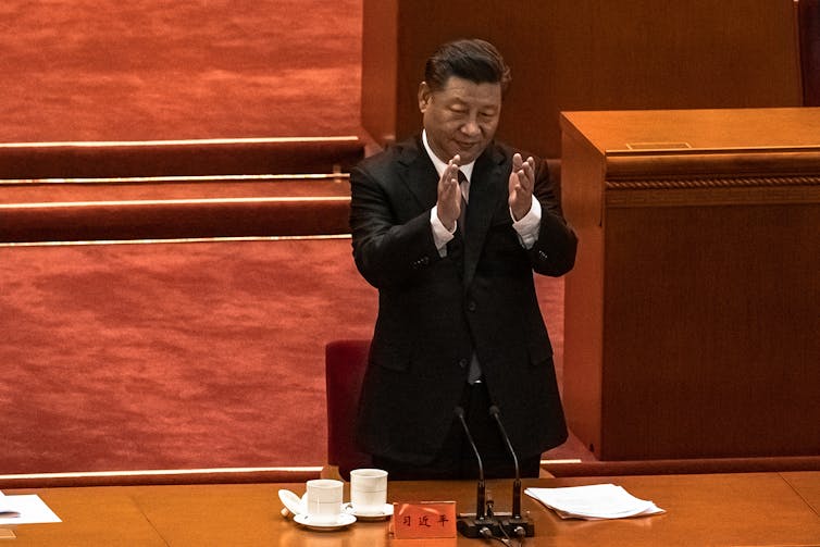 Xi Jinping applauding at a conference
