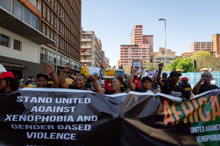 Marchers led by mostly women raise clenched fists and carry a huge black banner with white capital letters saying 'Stand united against xenophobia and gender-based violence' in Johannesburg