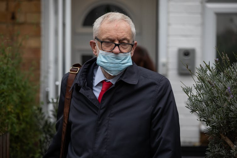 Jeremy Corbyn wearing a covid mask over his mouth.