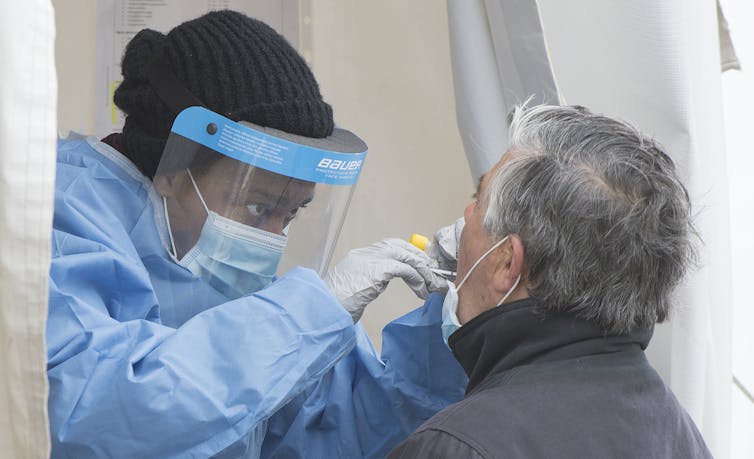 A health-care worker swabs a man at a walk-in COVID-19 test clinic.