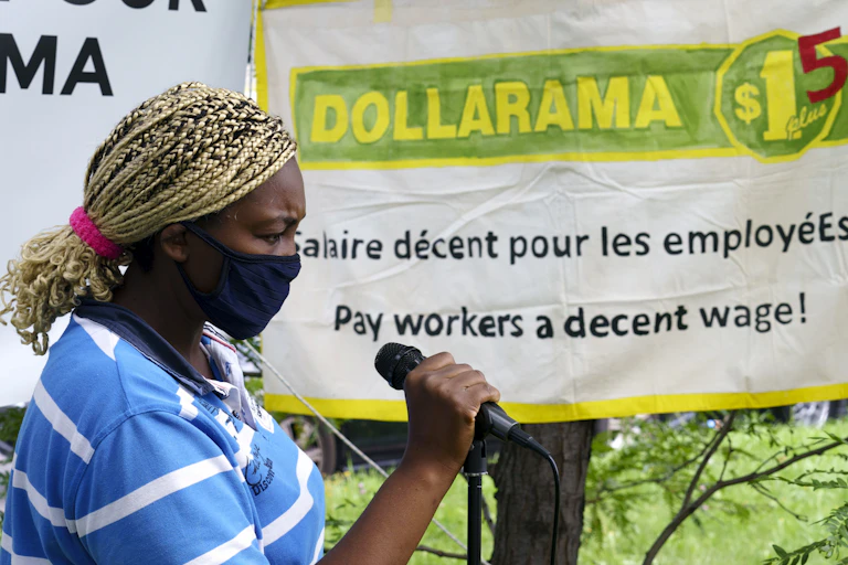 A Black woman wearing a mask speaks into a microphone.