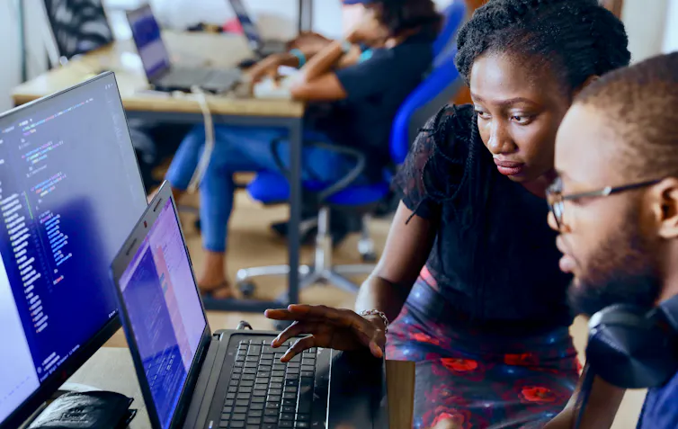 A Black woman and man look at a laptop screen.