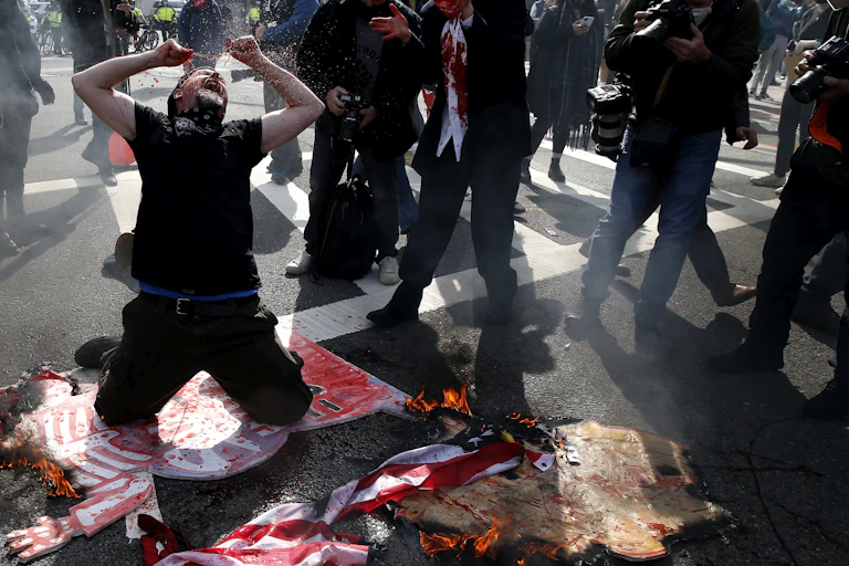 A protester dressed in black drops to his knees