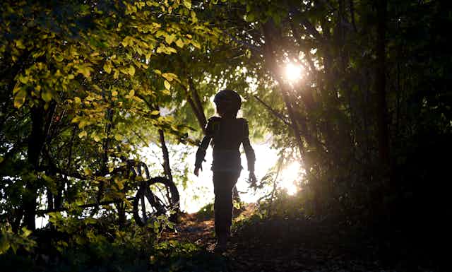 A child walks through a wooded area