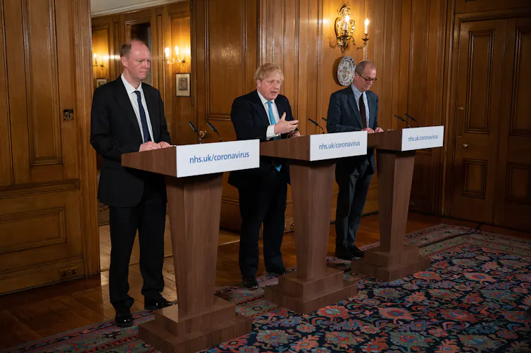 Chief Medical Officer Chris Whitty and chief scientific adviser Patrick Vallance look on as British prime minister Boris Johnson speaks at a coronavirus news conference inside number 10 Downing Street, London