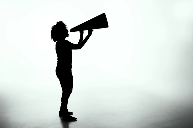 A silhouette of a woman speaking through a megaphone.