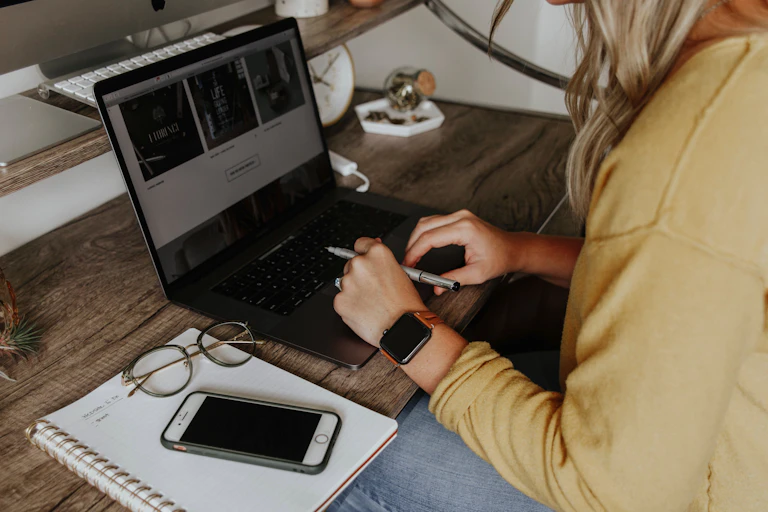 A woman sits at a desk in front of her laptop.