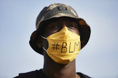 Man wearing face masks with a hashtag for Black Lives Matter.