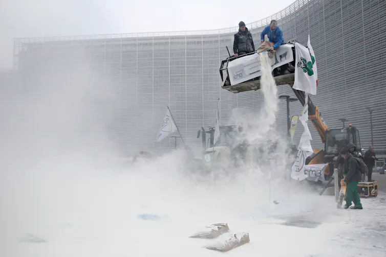 Protesting farmers dump milk powder from a platform outside the EU Parliament.