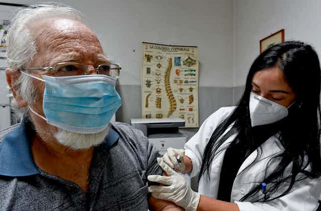 A medic administers a flu vaccine to an elderly patient