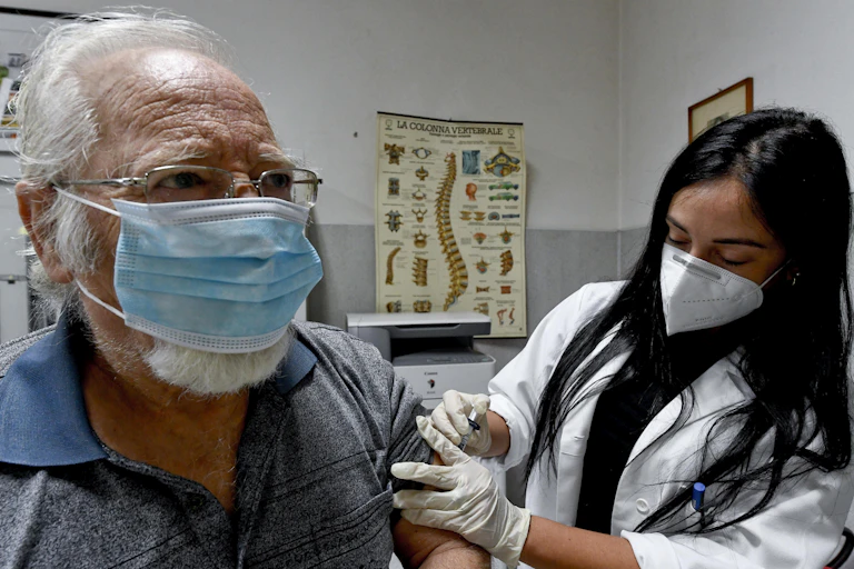 A medic administers a flu vaccine to an elderly patient