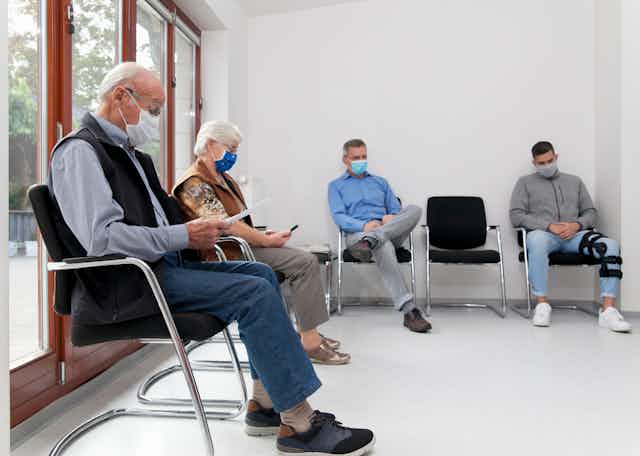Cuatro personas con mascarilla en una sala de espera.