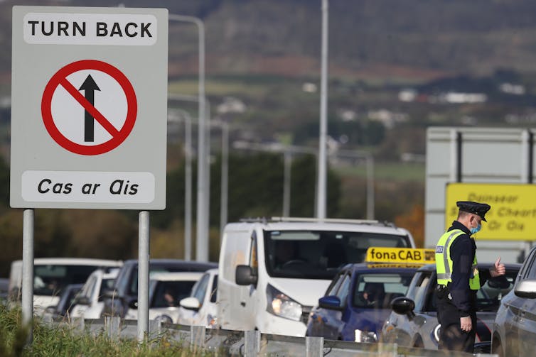 Cars queue at a sign that says