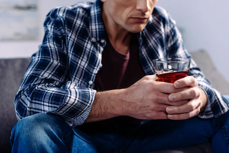 A man clutching a glass of alcohol.