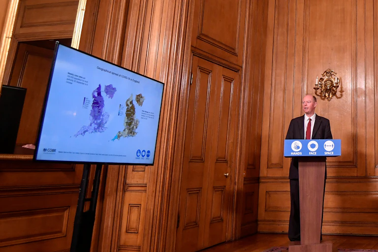 Chris Whitty presenting slides at a press conference