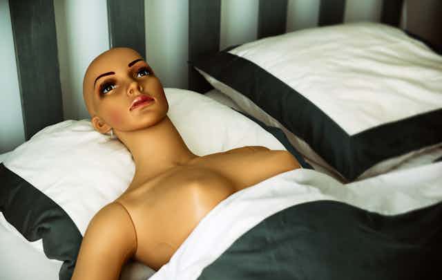 Naked plastic woman lying in bed.