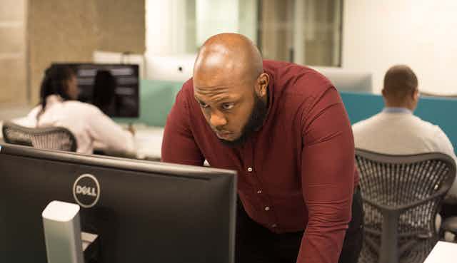 A Black man looks into a laptop screen.
