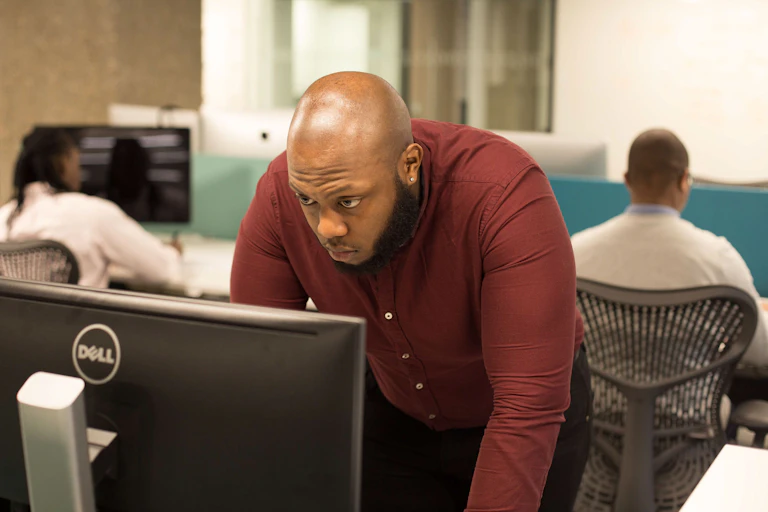 A Black man looks into a laptop screen.