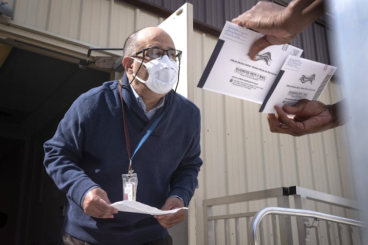 A man in a mask peers at election documents
