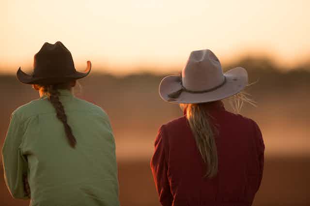 Two farmers facing away, looking at the sunset