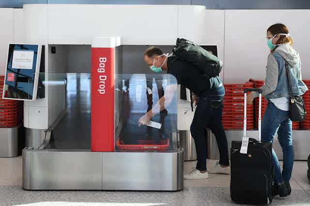 A man loads luggage onto a bag drop at Sydney airport.