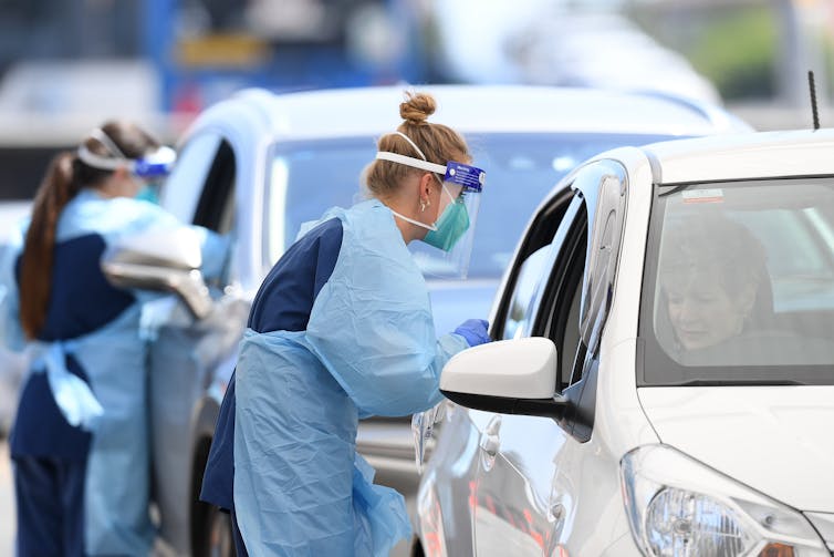 A health-care worker conducts a COVID test at a drive through testing site in Sydney.