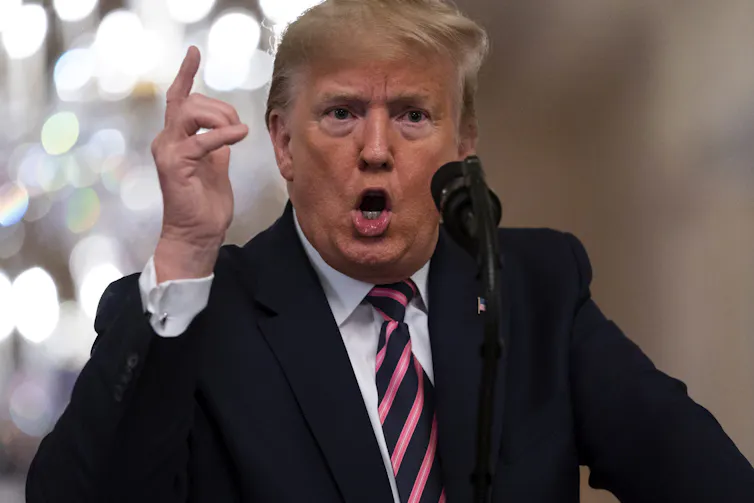 Trump is seen gesturing and talking into a microphone.