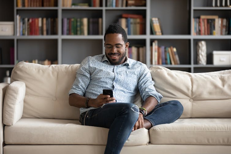 Man sitting on couch looking at his phone.