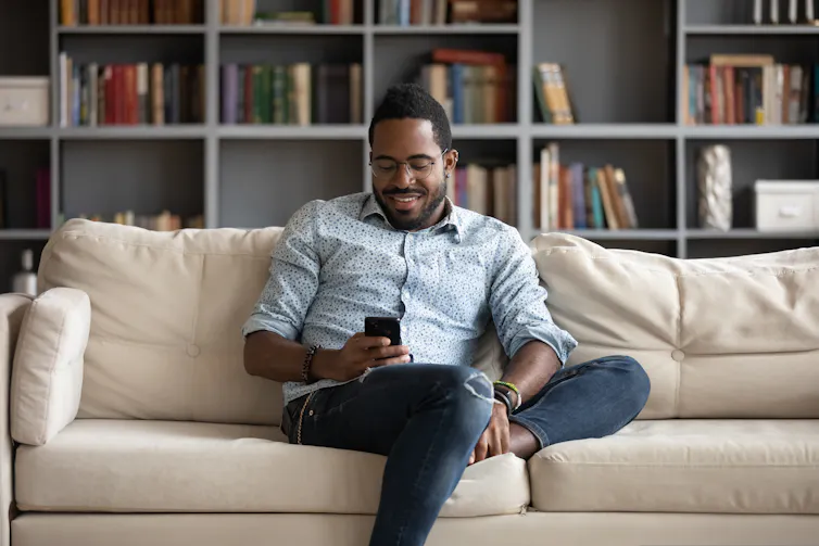 Man sitting on couch looking at his phone.