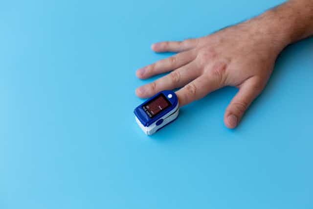 Pulse oximeter on a man's index finger.