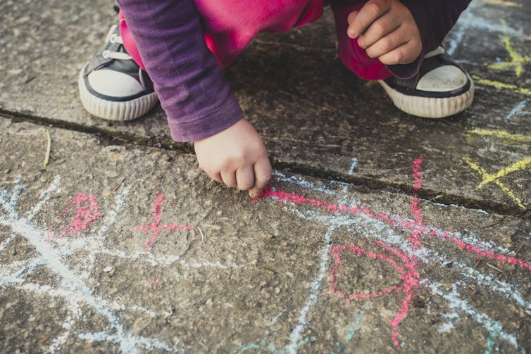 Child drawing with chalk on the ground