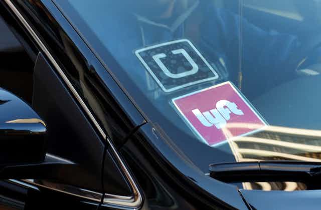 A ride-share car displays Lyft and Uber stickers on its front windshield in downtown Los Angeles.